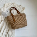 Bolso tote de paja tejida marrón con asas de cuero marrón sobre un fondo blanco - Caqui