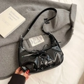 Shiny black hobo bag with lace-up detail and silver eyelets on a textured grey coat - Black
