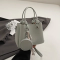 Detail view of mint green pebble leather bucket bag with a woven knot handle and mini pouch - Light Blue with Charm
