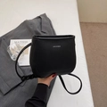 Bolso tipo cubo minimalista negro con textura de lichi, letras plateadas y correa cruzada - Negro