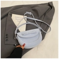 Bolso tipo silla de montar azul claro con lazo sobre un fondo de blazer gris elegante - Azul
