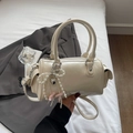Détail d'un sac Boston beige avec breloque nœud en perles et pendentif cœur élégant - Blanc Cassé Avec Pendentif