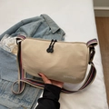 Chic beige dumpling bag with colorful striped strap and brand logo in a casual setup - Khaki