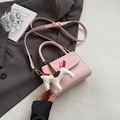 Pink minimalist handbag with a matching horse charm on a grey blazer backdrop - Pink