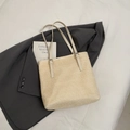 Schicke beige Stroh-Tote-Bag mit weißen Lederriemen auf einem dunkelgrauen Sakko - Abgesetzt Weiß Ohne Anhänger