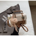 Detailed shot of leather crossbody bag with star accents and plush bear keychain - White & Khaki