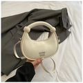 Chic beige crescent handbag with knotted handle and silver logo on elegant grey suit - White