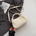 Cream-colored pleated handbag with knotted handle and adjustable strap in urban setting - White