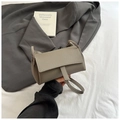 Detail view of lychee pattern leather and vertical buckle on the grey crossbody pillow bag - Gray