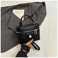 Detailed macro view of black lychee grain leather handbag with silver H-lock and hardware - Black