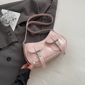 Bolso de hombro rosa tipo media luna con hebillas sobre una chaqueta gris de moda - Rosa