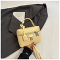 Detalle de bolso amarillo en piel con textura de lichi, cierre plateado y doble cremallera - Amarillo