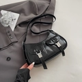 Borsa a tracolla nera lucida con tasche argentate su sfondo di un abito grigio - Nero