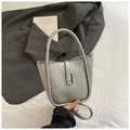 Dettaglio di borsa a secchiello intrecciata argento con texture metallica su lenzuola - Argento
