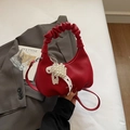 Close-up of red leather crossbody bag with cloud pleated handle and pearl bow pendant - Wine Red Without Pendant