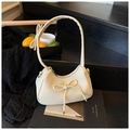 Minimalist beige dumpling bag with bow accent in lychee grain leather finish - White