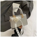 Detail van zilveren metallic handtas met parelhart hanger en kanten strik decoratie - Zilver