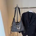 Detail of silver butterfly buckle and pearl chain on a grey glitter hobo shoulder bag - Black