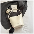 Detailed macro view of cream crocodile-embossed bucket bag with bottom silver studs - White