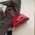 Glänzende weinrote Schultertasche mit Schleife vor schickem Anzug-Hintergrund - Rot