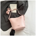 Detailed view of pink crocodile pattern bucket bag with metal protective feet and strap - Pink