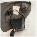 Detail view of black crocodile pattern bucket bag with metal studs and detachable strap - Black