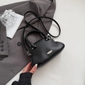 Elegant black lychee grain mini shell bag with silver hardware on a gray blazer backdrop - Black