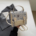 Détail d'un sac bandoulière crème avec motif ours mignon et boucles de fermeture - Rayé
