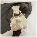 Detail of cream bucket bag featuring elegant lace bow and layered pearl charms accessory - Cream White with Pendant