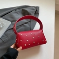 Red retro handbag with silver studs and lychee texture on grey blazer background - Red