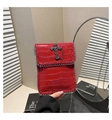Detail of red crocodile pattern handbag with silver cross charm and punk metal chain edges - Red
