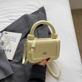 Détail du petit sac à main minimaliste jaune pâle en cuir avec poignée ronde et logo - Jaune