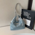Detalle de bolso denim azul claro con asas plateadas y lazo de encaje blanco - Azul cielo con colgante