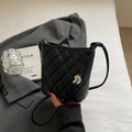 Detailed close-up of black quilted bucket bag with liquid metal pendant detail - Black