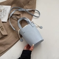Dettaglio borsa a secchiello celeste con motivo litchi, coulisse e finiture argento - Blu