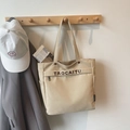Dettaglio della borsa tote in tela con tasca laterale, tasca con zip e scritte del marchio - Cachi
