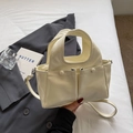 Dettaglio di una borsa a mano crema su un letto bianco con blazer alla moda - Bianco Sporco