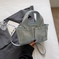 Dettaglio borsa a mano celeste in pelle con tasche frontali e manico integrato raffinato - Blu