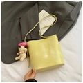 Detalle de bolso cubo amarillo con colgante de oso sobre blazer y sábanas - Amarillo con colgante