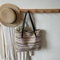 Detail einer gewebten gestreiften Tragetasche mit Lederriemen im Lifestyle-Ambiente - Khaki