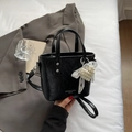 Bolso tipo cubo negro chic con textura plisada, dije de corazón de perlas y bandolera - Negro