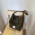 Dettaglio della borsa tote in tela leopardata con etichetta su una sedia di legno - Stampa leopardata