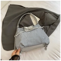 Dettaglio borsa a pieghe argento con coulisse a fiocco su sfondo di blazer grigio - Blu