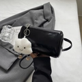 Detail einer schwarzen glänzenden Zylindertasche mit süßem Plüsch-Wolkenanhänger - Schwarz Mit Anhänger