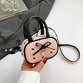 Pink pleated crossbody bag with black bow details and heart charm held in hand - Pink