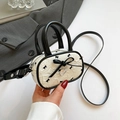 Chic cream crossbody bag with black bow print and heart charm in hand display - White