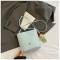 Detail of light blue woven bucket bag featuring metal logo and pearl charm accessory - Blue with Pendant