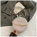 Detail der runden Tasche aus rosa Webstoff mit Goldkette und dekorativen Perlen - Rosa
