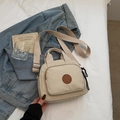 Close-up of beige canvas crossbody bag with round leather logo and dual zipper pockets - Off-white