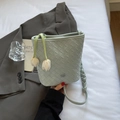 Mint green woven bucket bag featuring floral charms and braided shoulder strap detail - Blue